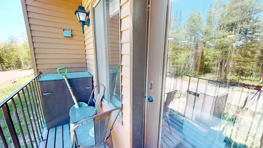 Private balcony featuring horizontal siding, exterior wall light fixture, and a solid railing