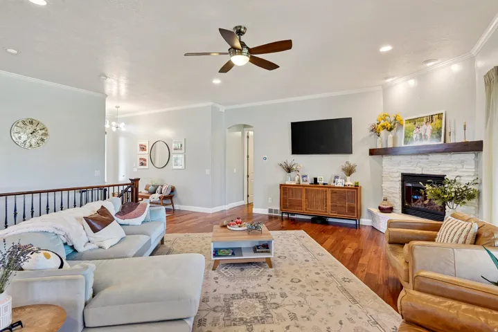 Hardwood flooring, recessed lighting, ceiling fan, corner fireplace with stone surround, and wood mantel