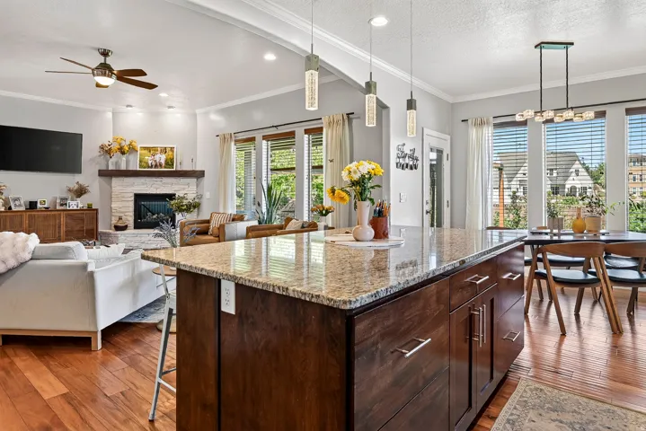 Gourmet kitchen island with stone countertop, rich wood-finish cabinetry, and pendant lighting