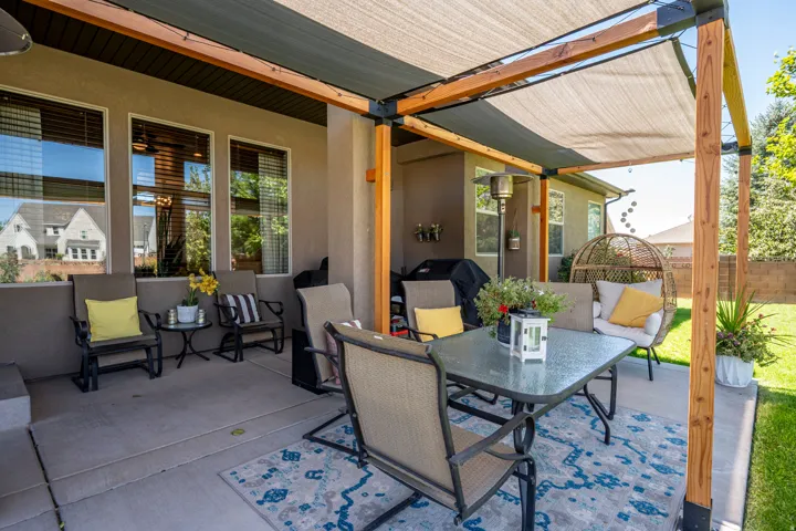 Expansive covered patio featuring a wood pergola with shade sails, a concrete surface, and direct access to a grassy yard
