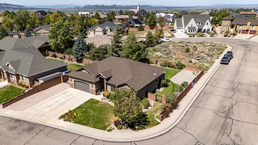 Expansive corner lot featuring a stucco and stone exterior, attached two-car garage, and established landscaping