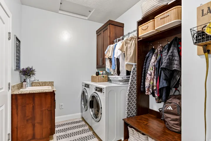 Laundry room with built-in cabinetry, under-mount sink, and light granite countertop