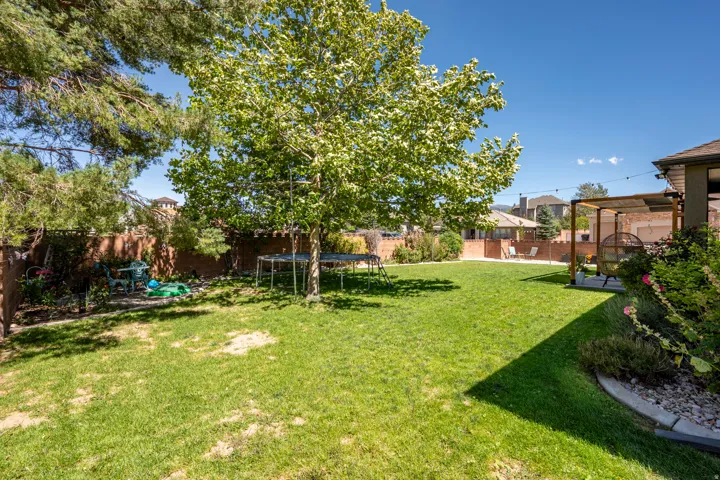 Expansive lawn with mature trees and a dedicated patio area featuring a pergola