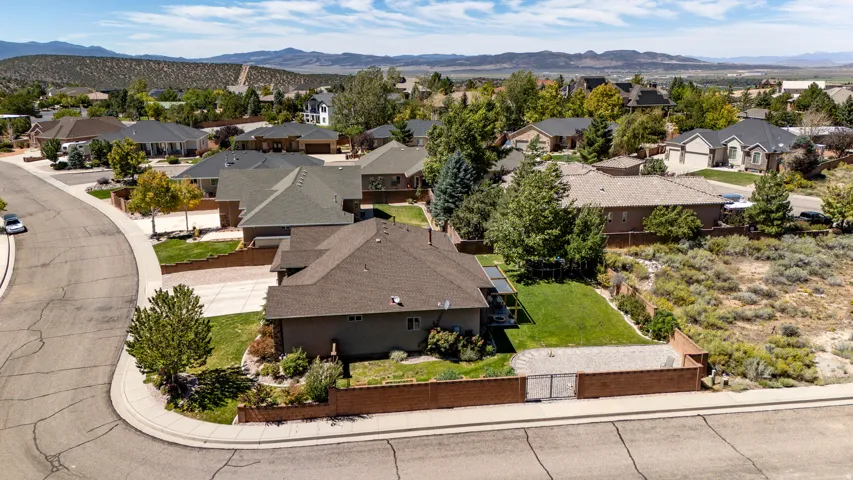 Residential property on a corner lot featuring a stucco exterior, a fenced backyard with a lawn area, and a paved driveway
