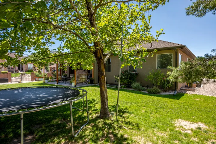 Expansive backyard featuring a green lawn, mature tree, and a shaded patio with a pergola