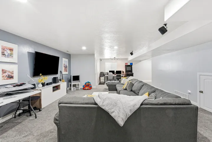 Recessed lighting, wall-mounted television, built-in shelving, carpet flooring, and a white door