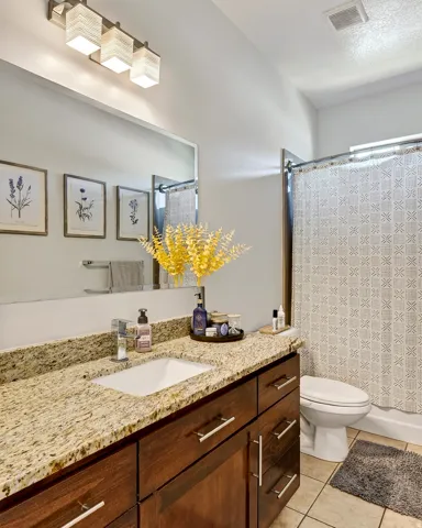 Bathroom featuring a single vanity with a granite countertop, undermount sink, and dark wood-finish cabinetry