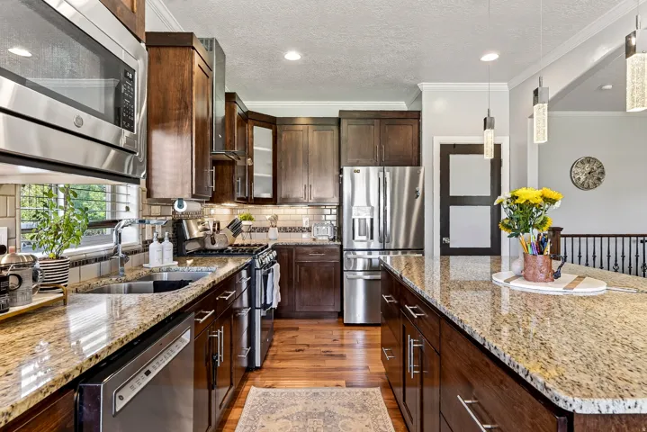 Kitchen featuring wood-finish flooring, dark wood cabinetry, stainless steel appliances, granite countertops, and recessed lighting