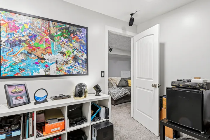 White interior door with arched paneling, built-in open shelving unit, and wall-mounted speaker