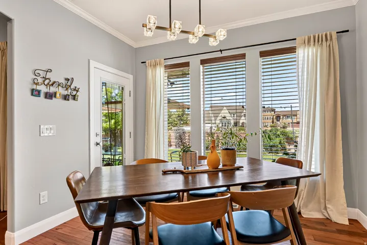 Hardwood flooring, crown molding, a modern linear chandelier, and a glass-paneled door