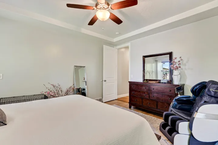 Tray ceiling with crown molding, ceiling fan with integrated lighting, light-toned wall paint, white trim, and wood-finish flooring