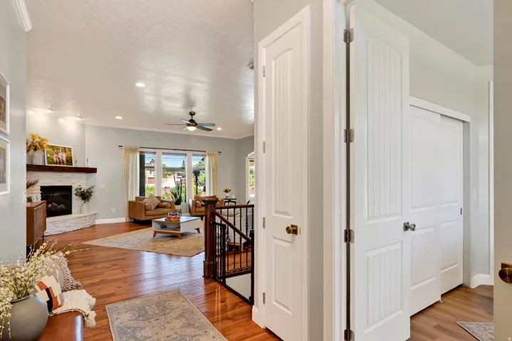 Open-concept living area featuring wood-finish flooring, a white brick-finish fireplace with a wood mantel, recessed lighting, and a ceiling fan