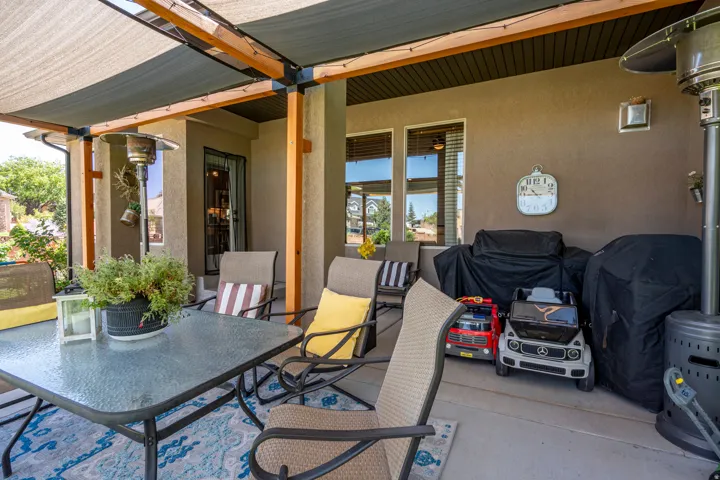 Covered patio featuring a slatted roof, exposed wood beams, stucco exterior, and multiple windows