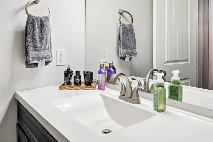 White vanity with integrated sink, brushed nickel faucet, and a large wall-mounted mirror