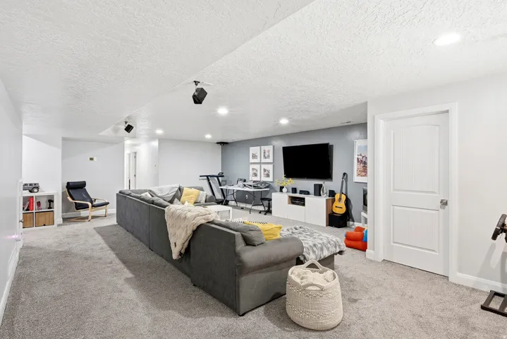 Recessed lighting illuminates the open living space, featuring a media console with integrated storage, and a paneled interior door