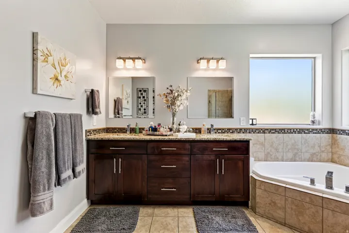 Dual vanities with stone countertops, individual mirrors, and vanity lighting