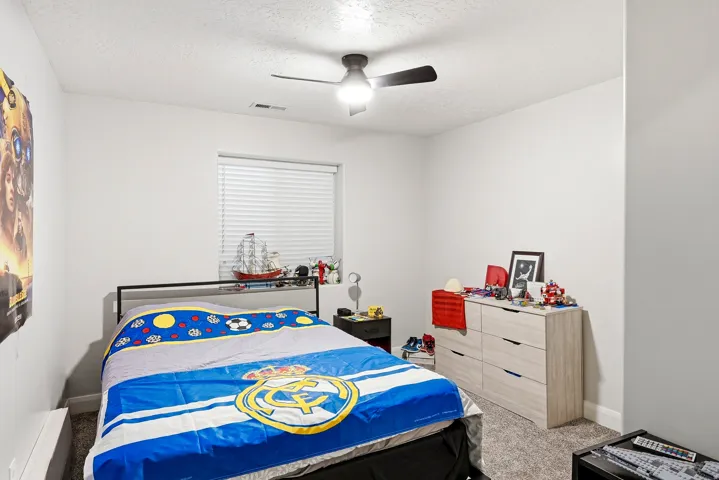 Carpeted room featuring a ceiling fan with light, a window with horizontal blinds, and light-toned walls