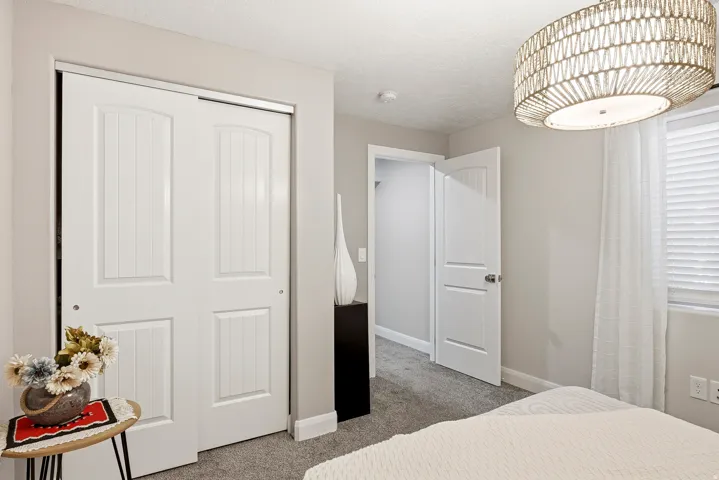 Sliding panel closet doors, neutral wall paint, textured ceiling, and a decorative woven light fixture