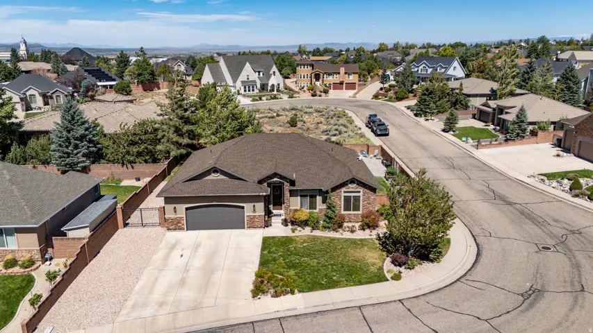 Paved driveway leading to an attached garage, with a manicured front lawn and established landscaping
