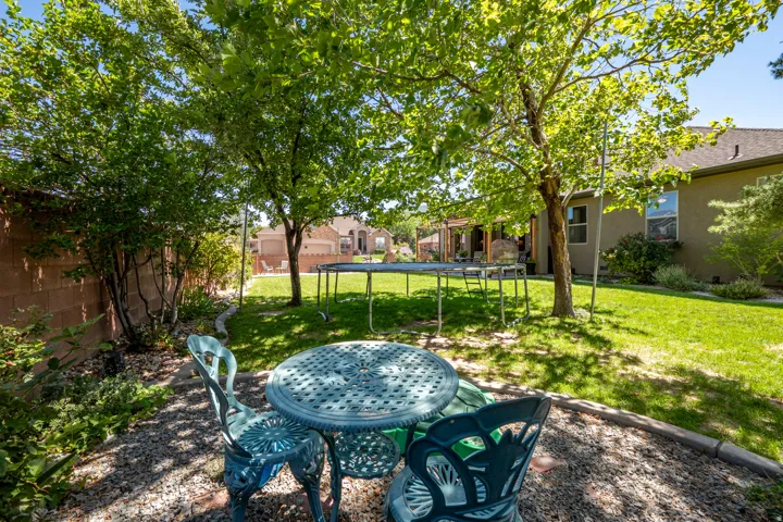 Expansive backyard featuring a manicured lawn, established trees, and a gravel patio area
