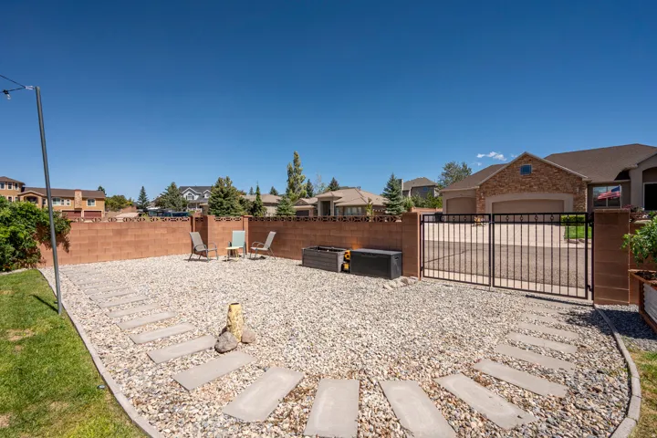 Gravel patio area with concrete stepping stones, block wall enclosure, and a wrought iron gate