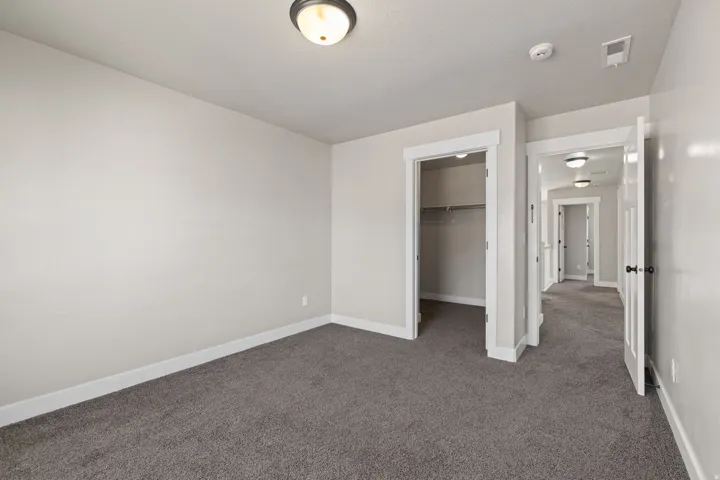 Neutral wall paint, plush carpet flooring, recessed ceiling light fixtures, white trim, and a closet with built-in shelving