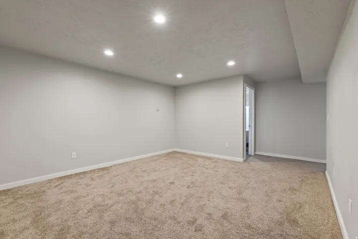 Spacious room with recessed lighting, light-toned carpeting, and neutral wall tones