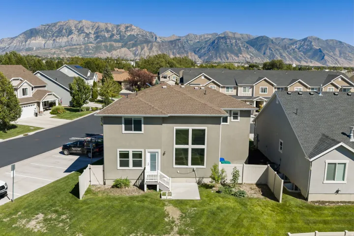 Rear exterior featuring a ground-level patio, white railing stairs, and multiple large windows