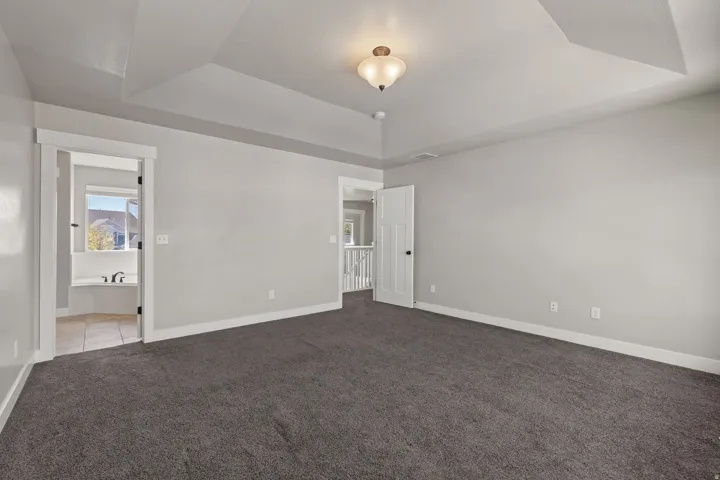 Tray ceiling, recessed lighting, wall-to-wall carpeting, white trim, and a white paneled door