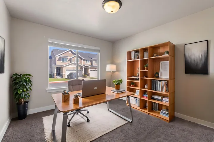 Recessed lighting, large window with roller shades, built-in shelving, and neutral wall paint