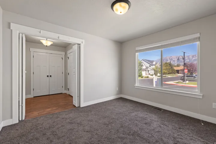 Spacious room featuring neutral carpeting, a large window, and a mountain backdrop