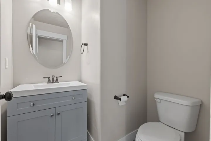 Vanity with integrated sink, oval mirror, wall-mounted light fixture, and two-door cabinet