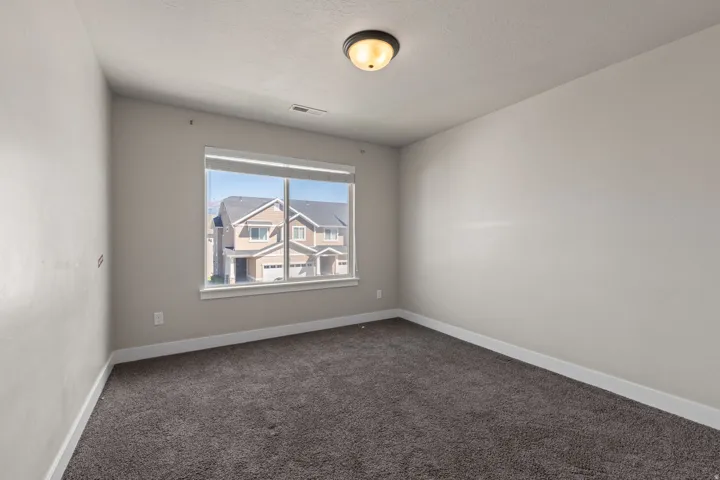 Recessed window, textured gray carpeting, white trim, and a flush-mount ceiling light