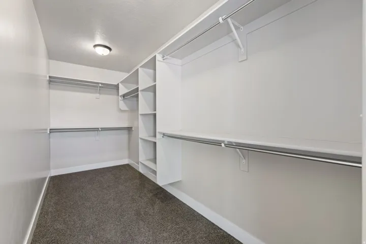 Custom closet system featuring multiple hanging rods, built-in shelving, and neutral wall paint
