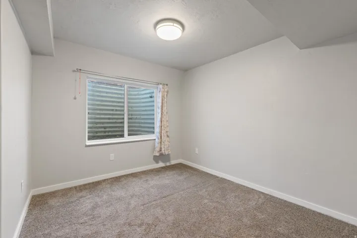 Neutral tone walls, recessed window, and gray carpet flooring