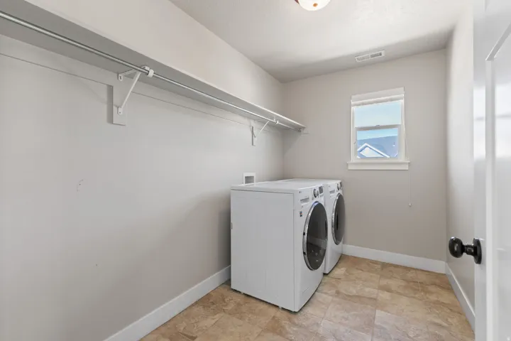 Laundry area featuring a window, tile flooring, and integrated shelving with a hanging rod