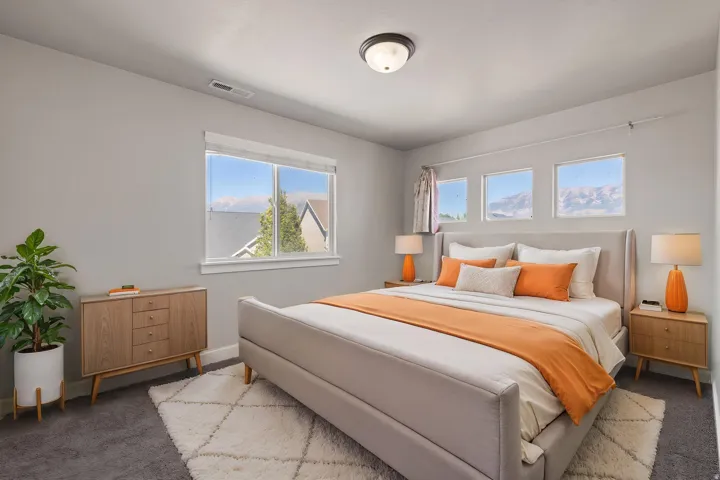 Plush carpeting, a modern ceiling light fixture, and multiple windows offering natural light and mountain scenery