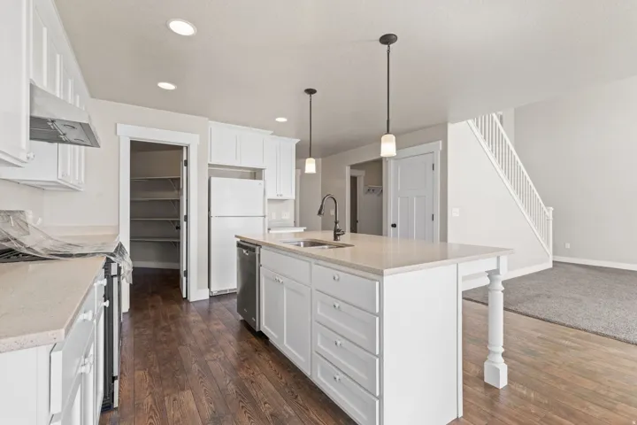 Kitchen featuring wood-finish flooring, white cabinetry, a center island with pendant lighting, and stainless steel appliances