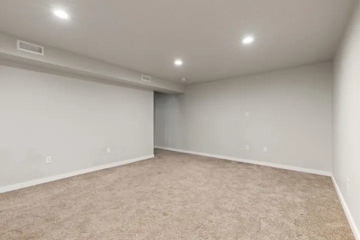 Spacious room with recessed lighting and neutral carpeting