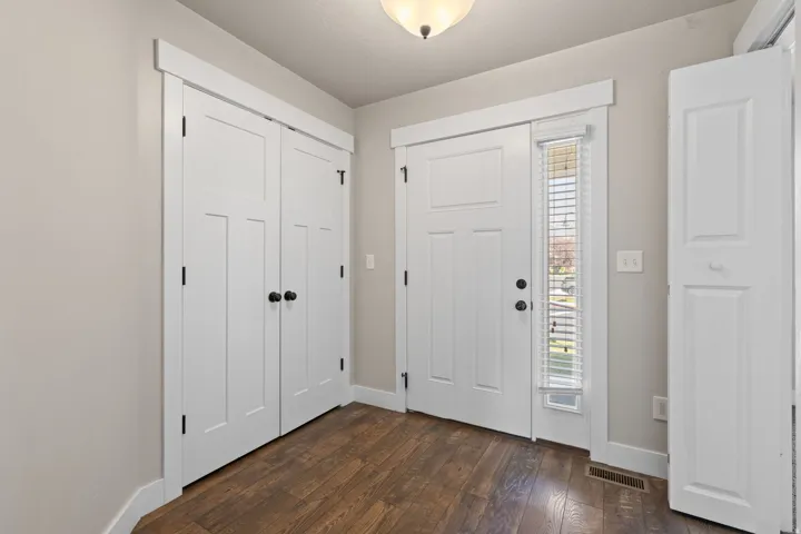 Wood-finish flooring, white panel doors, and a side-light entry door