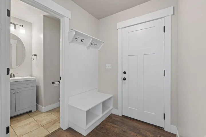 Built-in entryway bench with storage, wood-finish flooring, and a three-panel door