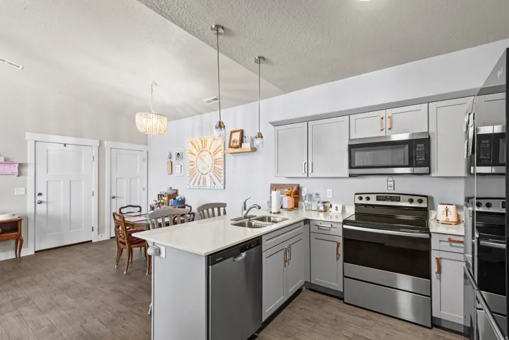 Kitchen featuring light gray cabinetry, stainless steel appliances, white countertops, and wood-finish flooring