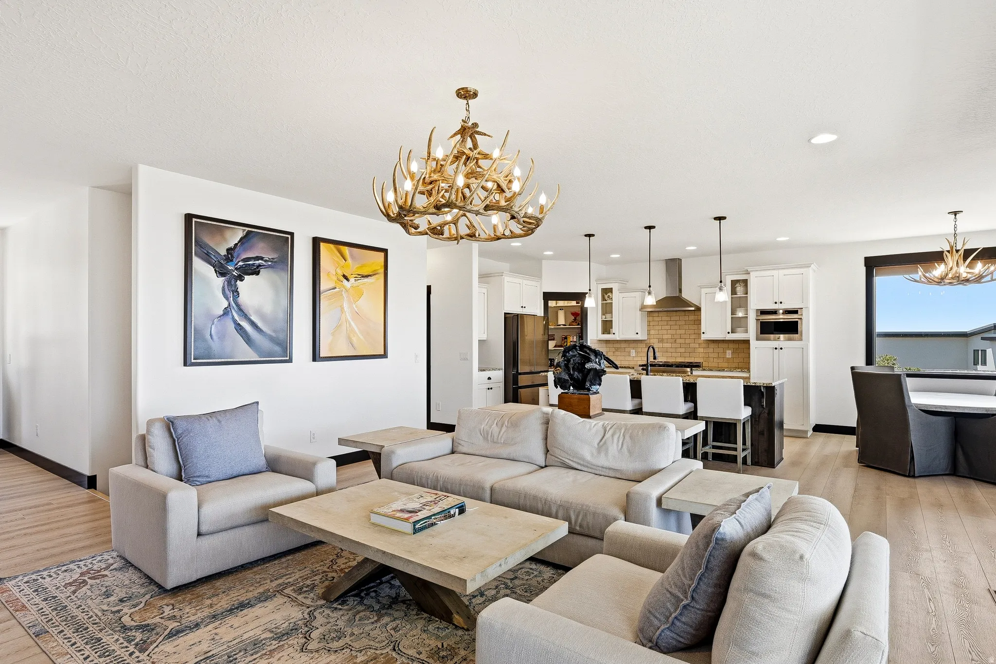 Open-concept living space featuring wood-finish flooring, a decorative antler-style chandelier, and recessed lighting