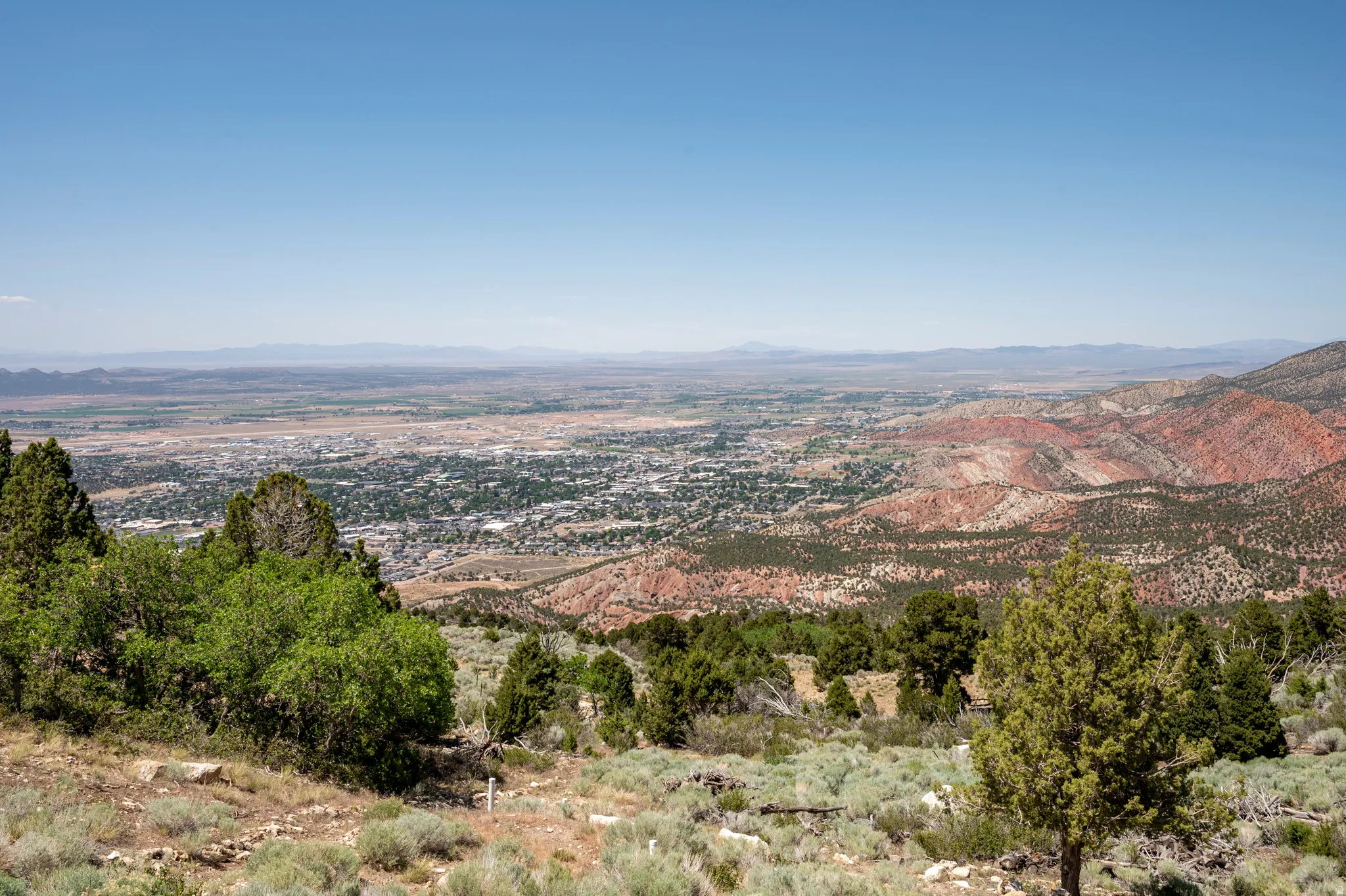 Expansive mountain landscape featuring broad valley and distant city