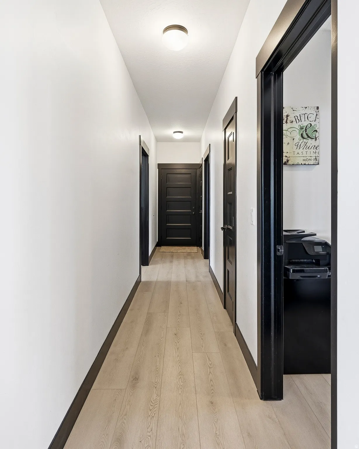 Hallway featuring light wood-finish flooring, white walls, and dark trim