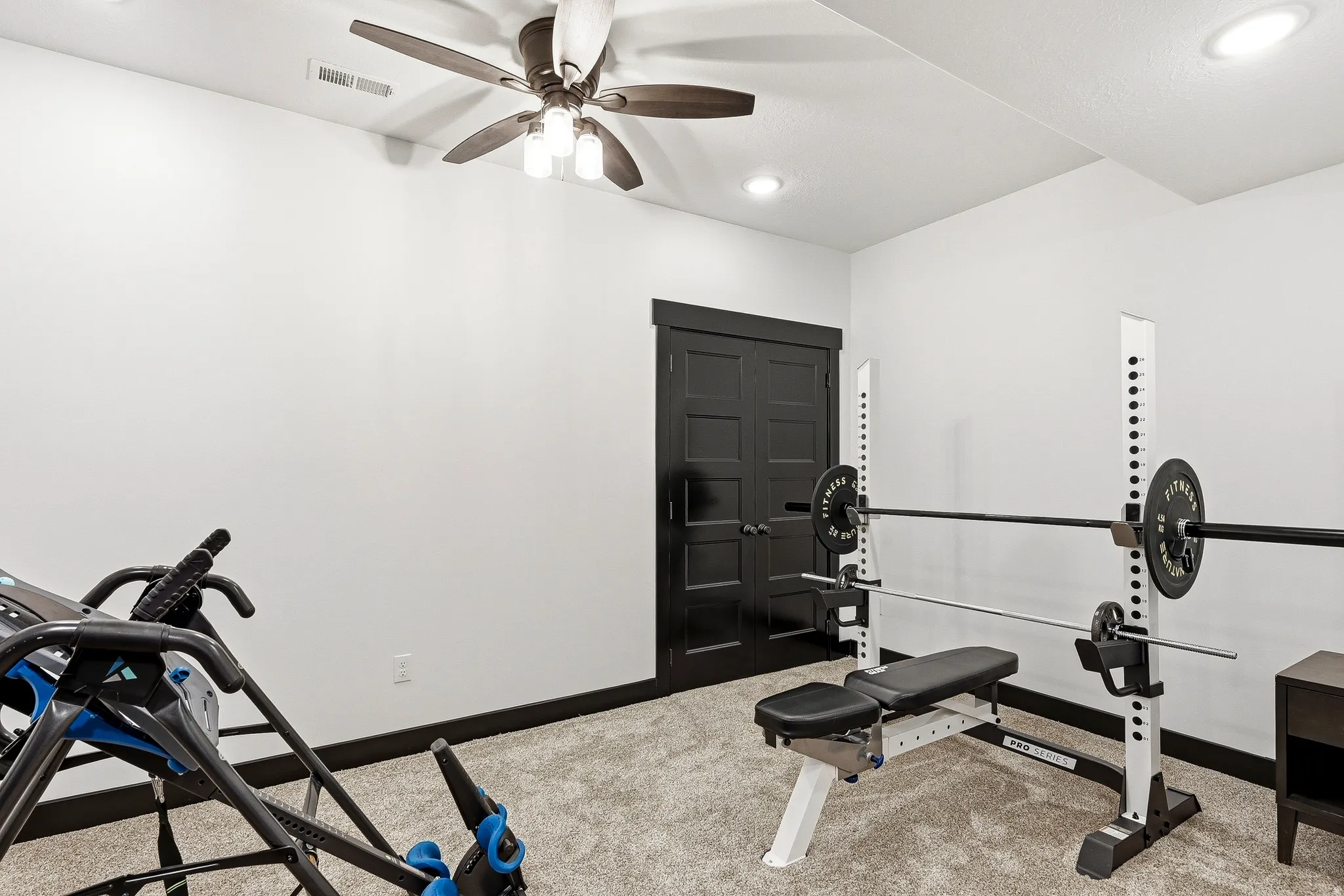 Recessed lighting, ceiling fan, dark wood-finish trim, black paneled doors, and grey textured carpeting