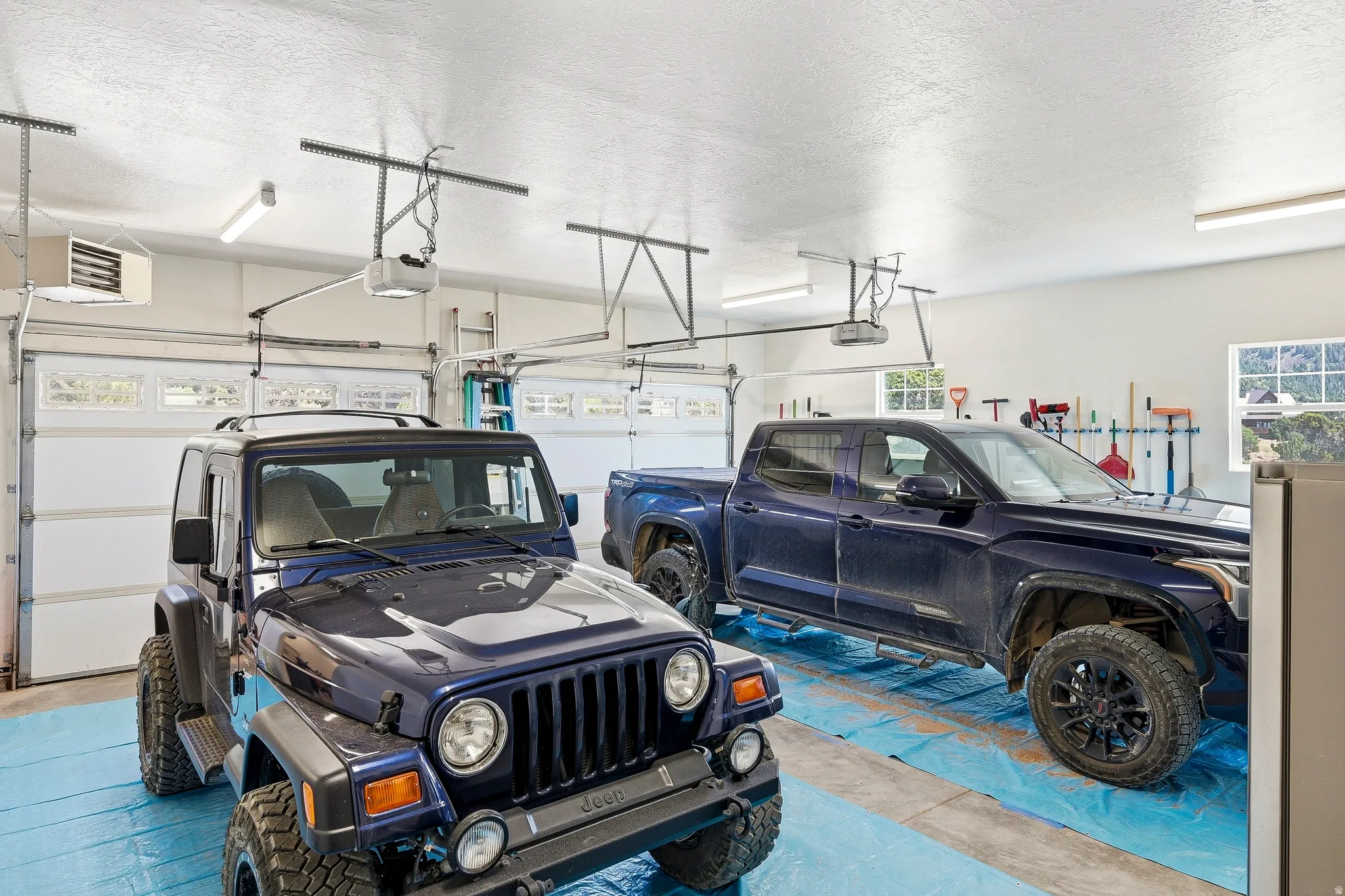 Two-car garage with overhead doors, concrete flooring, overhead lighting, and two windows