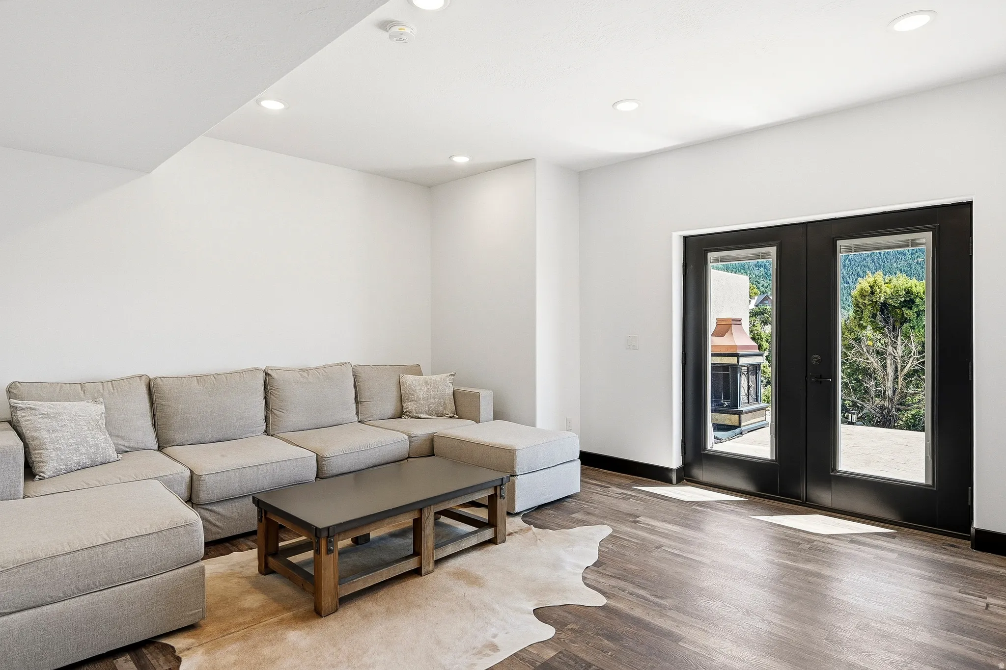Recessed lighting illuminates the room, featuring wood-finish flooring and white walls