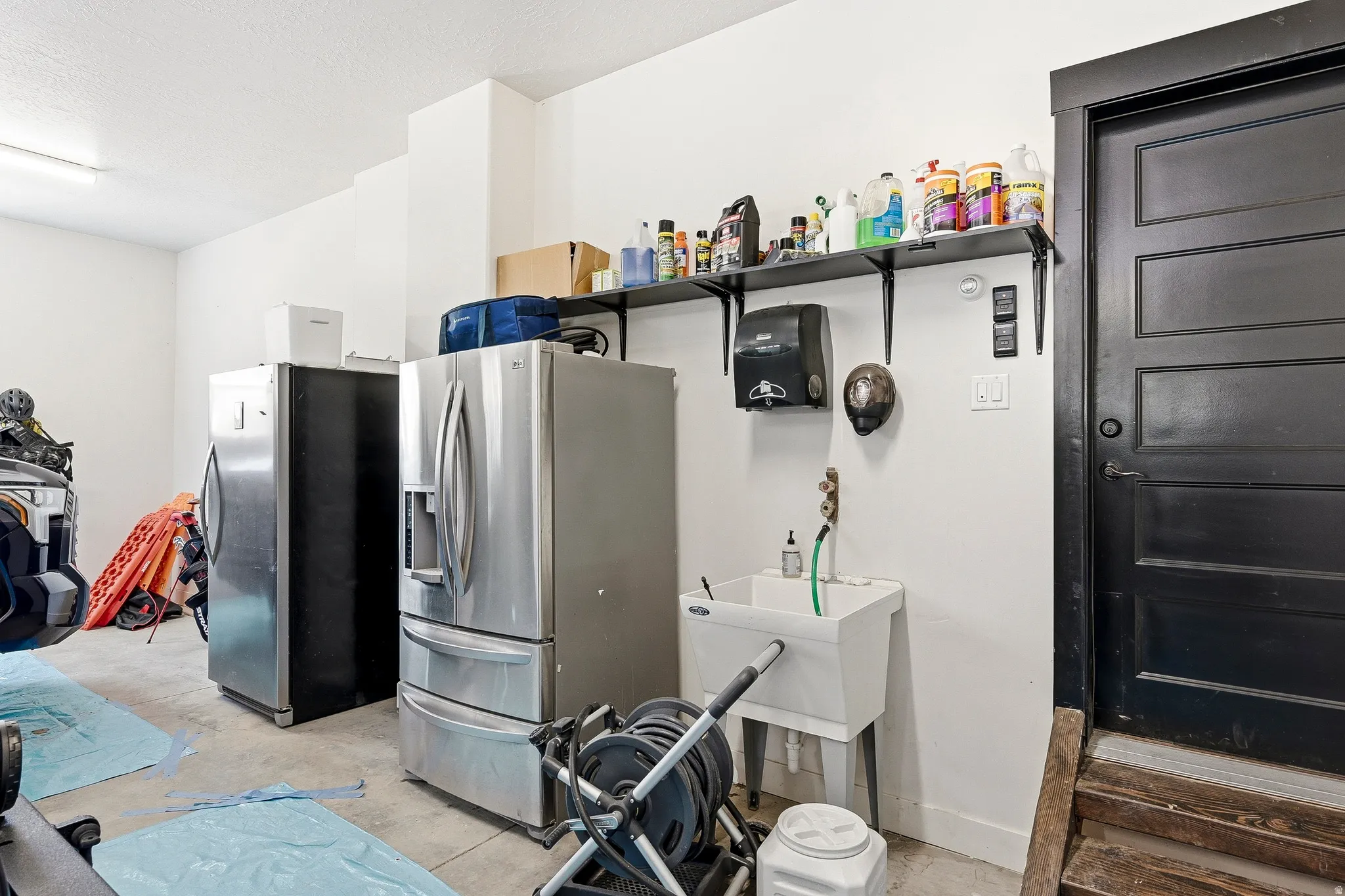 Black paneled door, wall-mounted shelving, and utility sink
