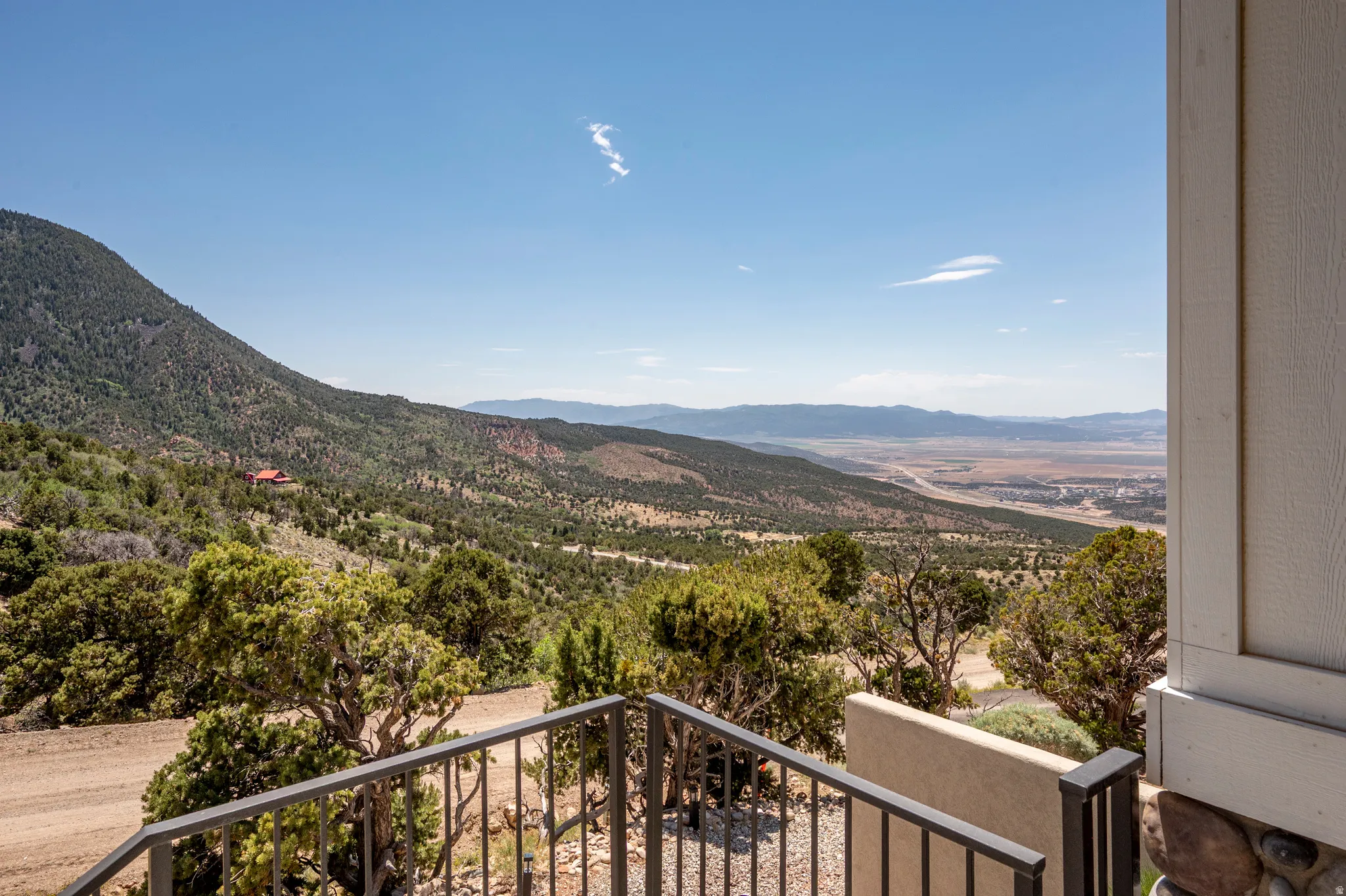 Expansive mountainous landscape with distant valley and a partially visible exterior wall